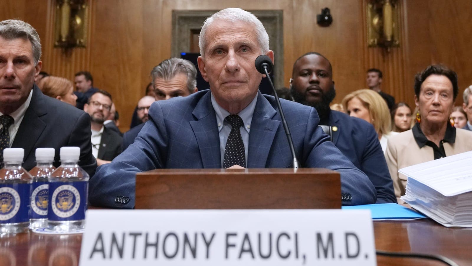 Anthony Fauci seated at a witness table before a Senate committee, hands folded in front of a microphone.
