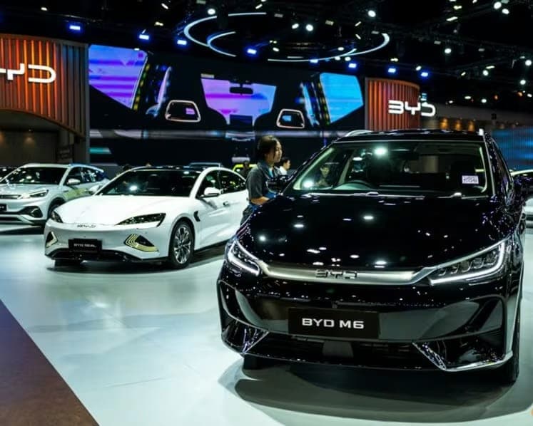 BYD electric cars on a brightly lit motor show stand.