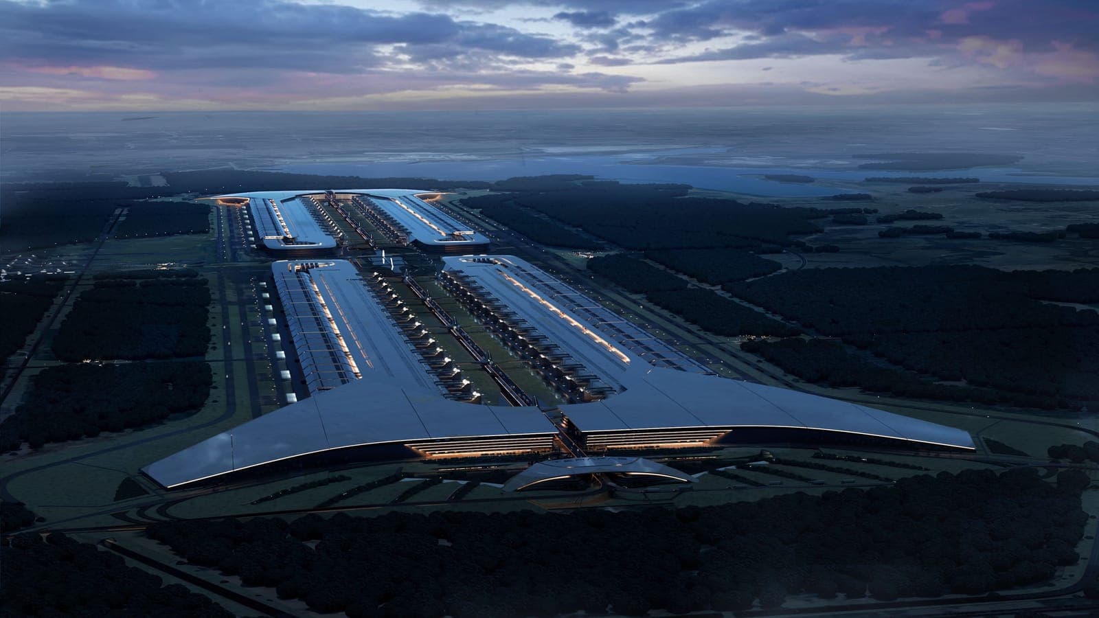 An aerial view at dusk of a vast industrial semiconductor facility beside water.