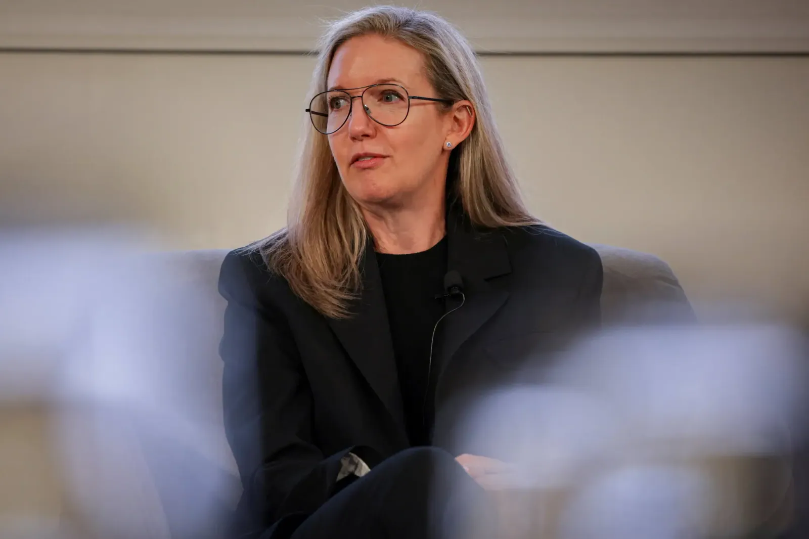 Julie Masino in a black jacket and glasses, seated and speaking at an event.