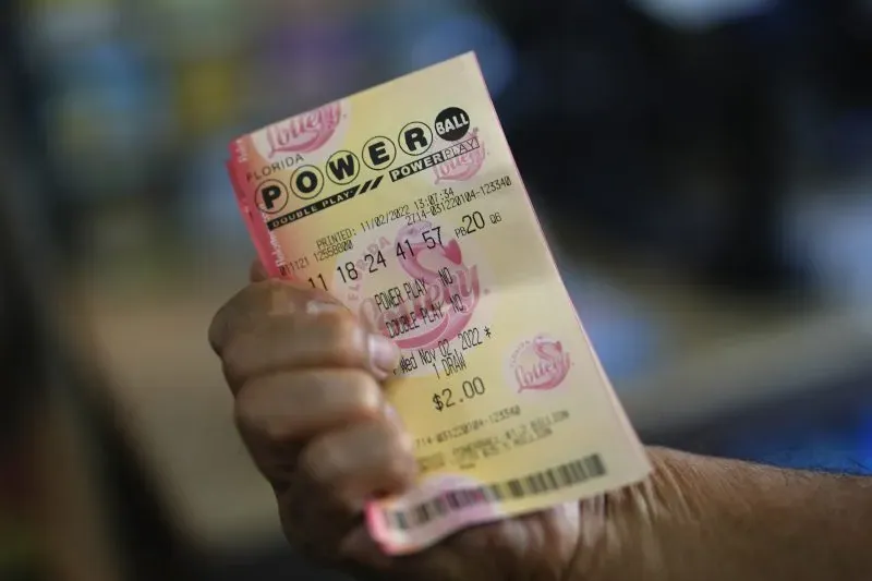 A hand holding a Florida Lottery Powerball ticket inside a convenience store.