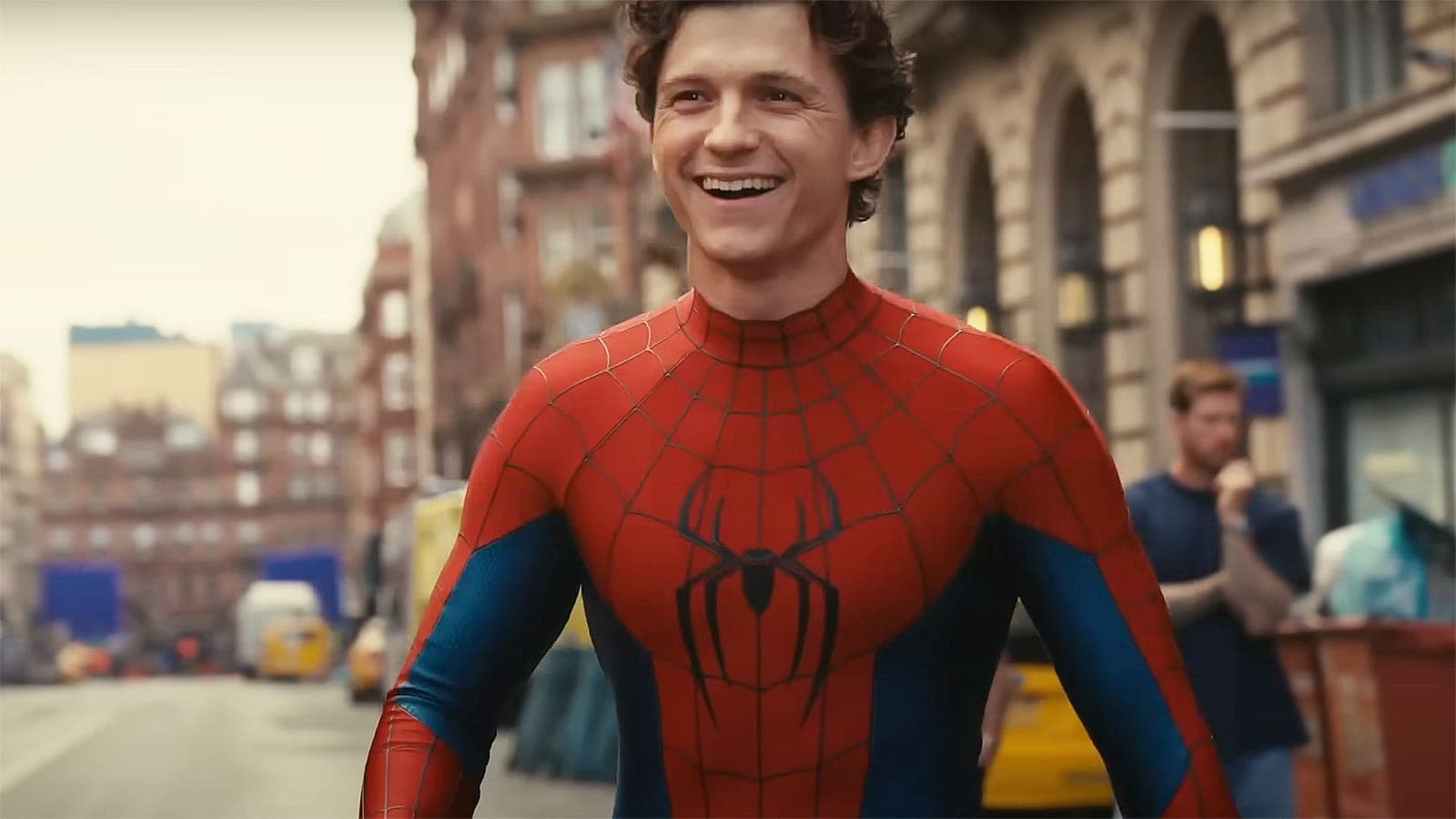 Spider-Man in his red and blue suit, mask off, standing on a New York street.