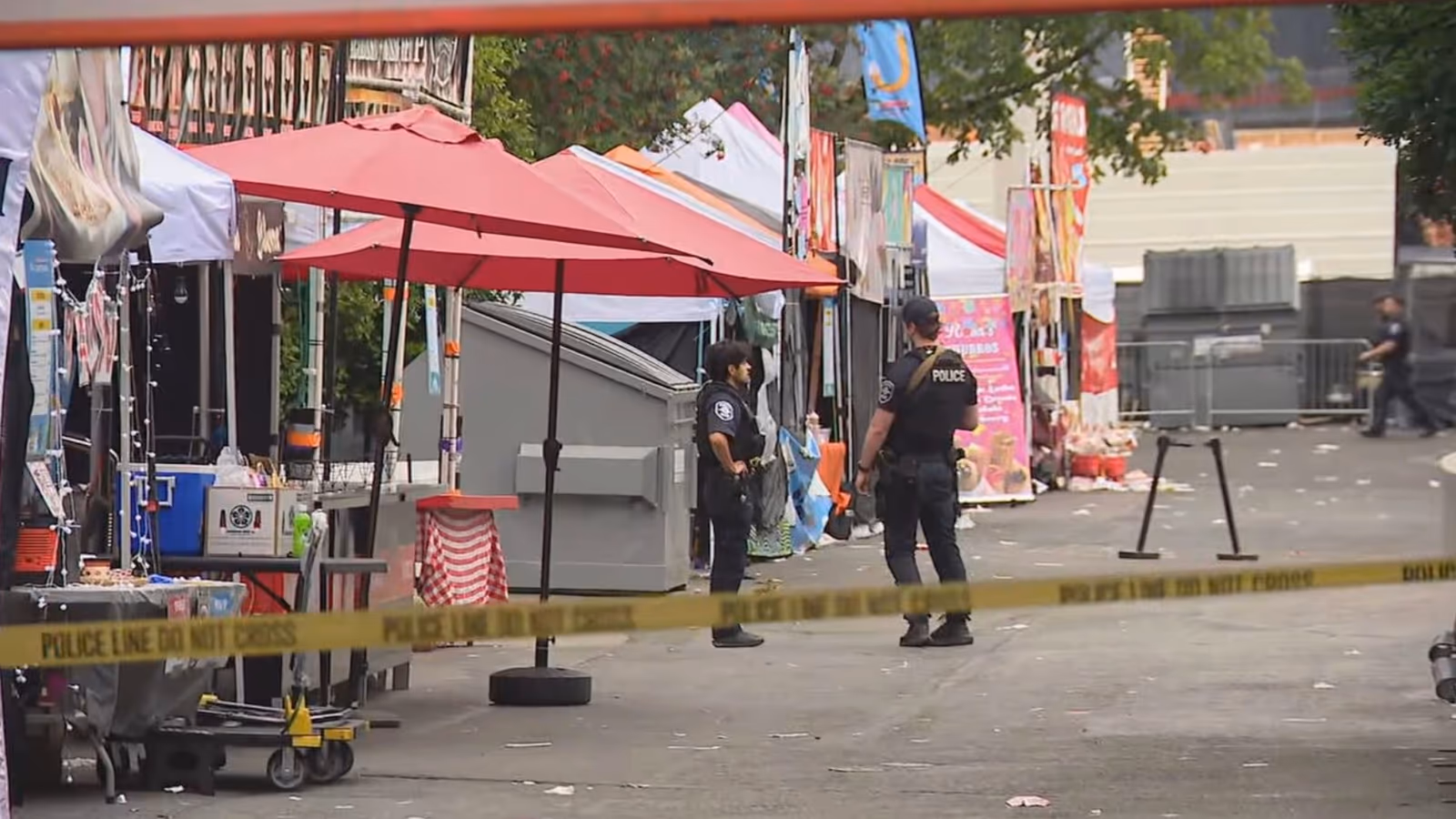 A police officer walking past food vendor booths and red canopies at Seattle Center after the shooting.