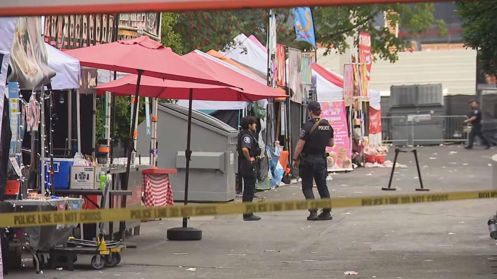 A police officer walking past food vendor booths and red canopies at Seattle Center after the shooting.