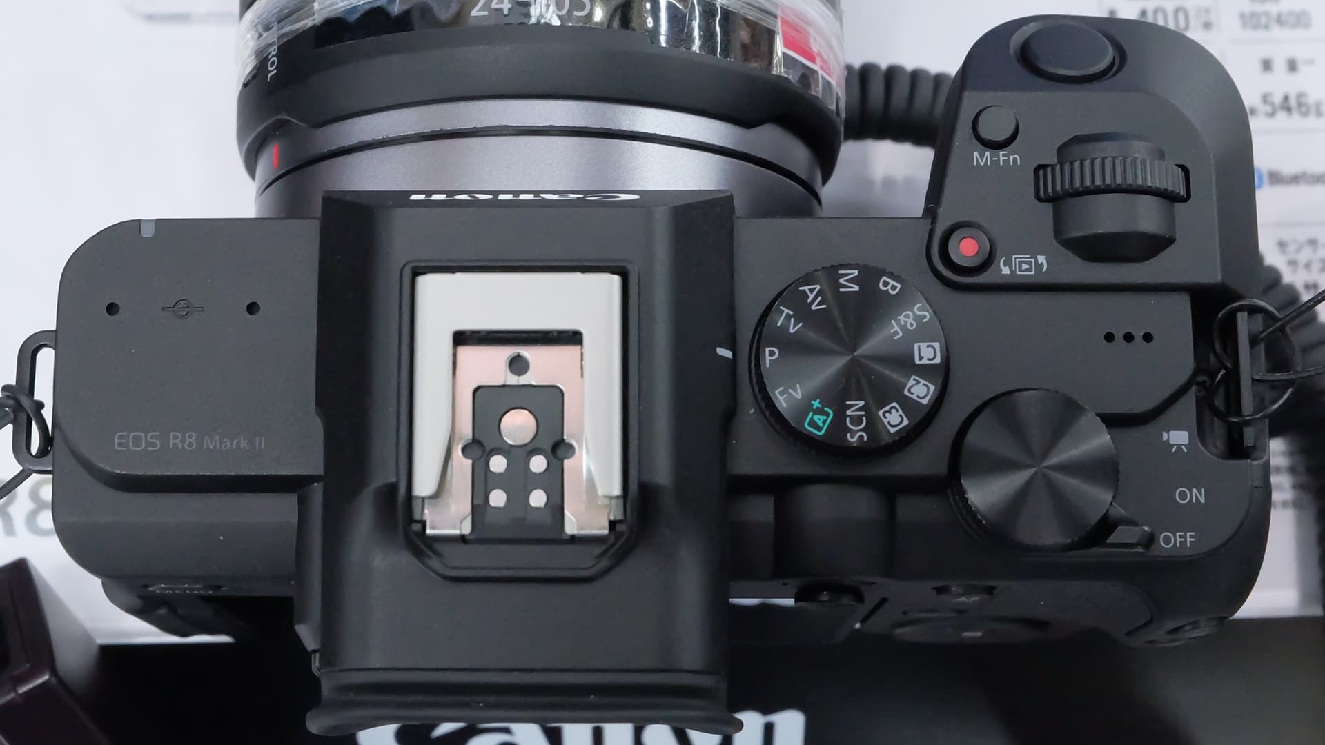 Overhead view of a black Canon EOS R8 Mark II camera body showing the hot shoe, mode dial with Fv and SCN settings, a red record button and an on/off switch with a video position.