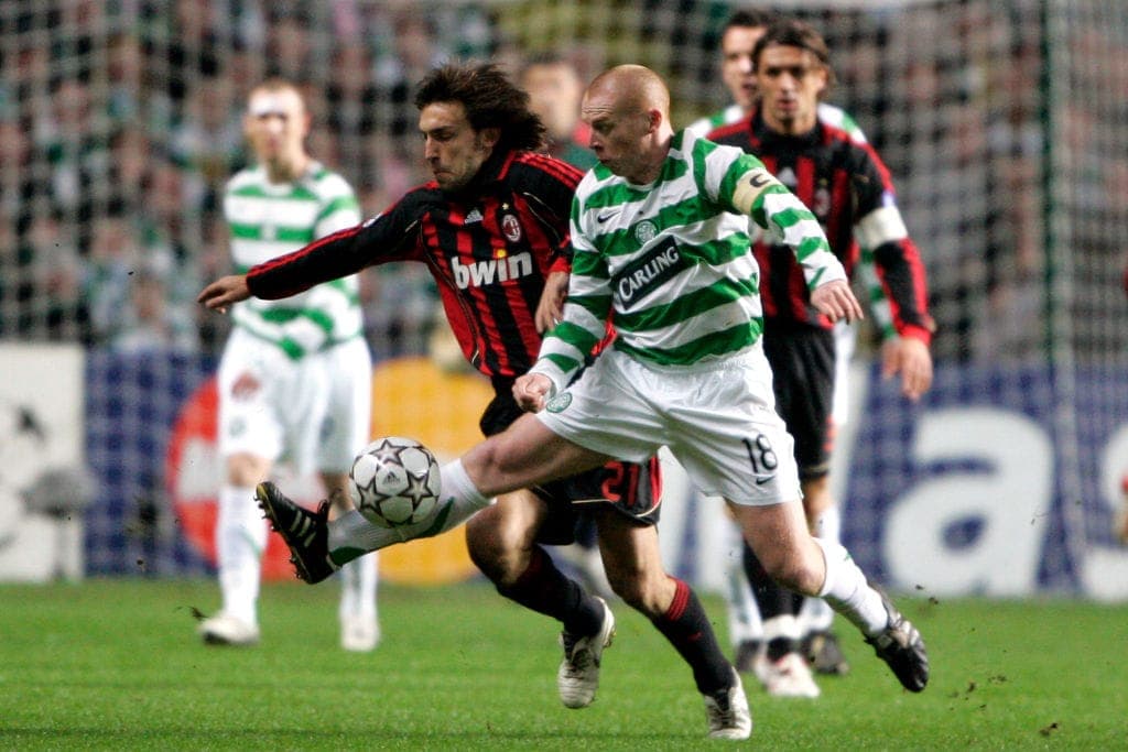 A Celtic player and an AC Milan player challenge for the ball during a match.