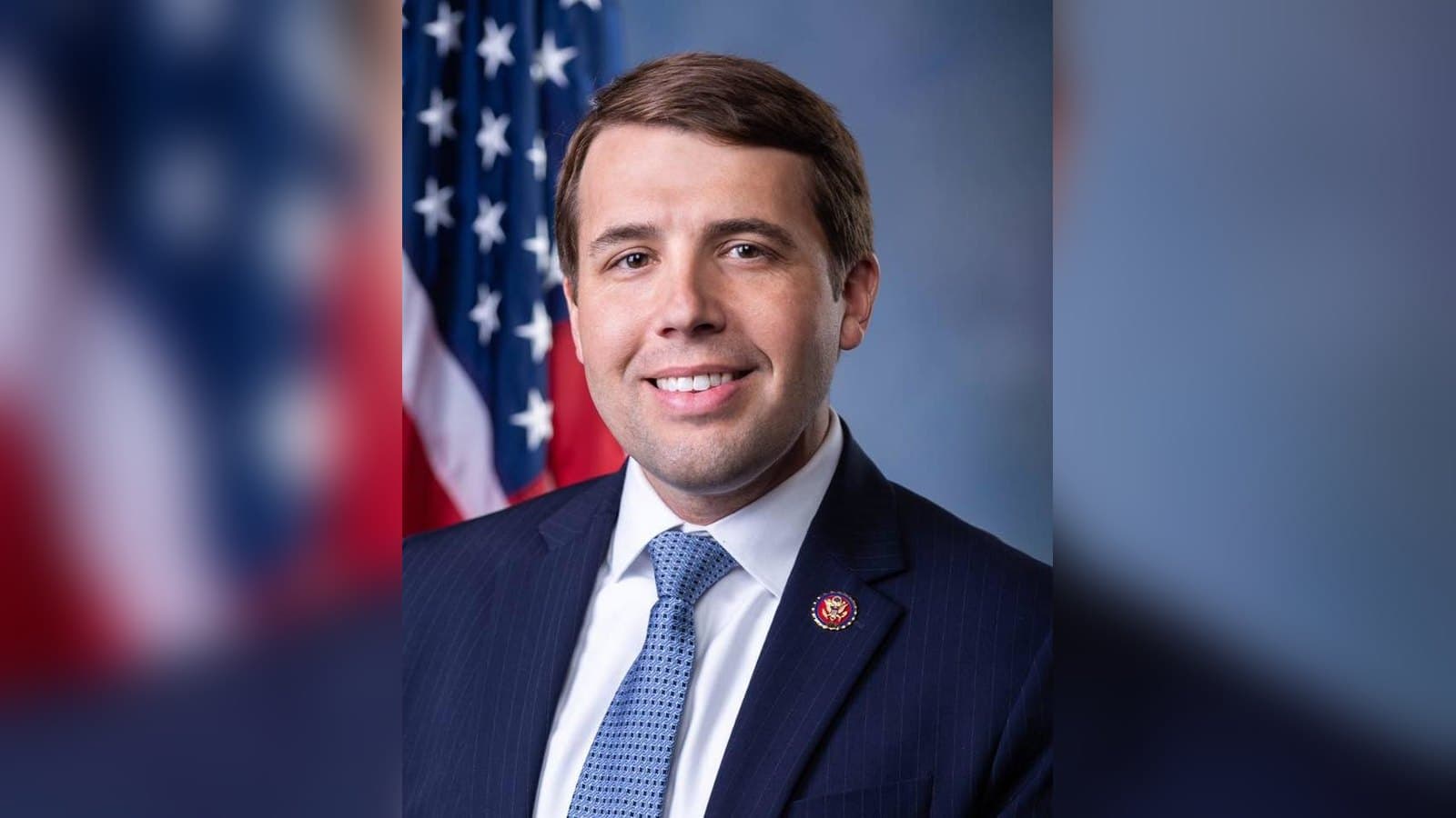 Official portrait of Chris Pappas in a dark suit and light blue tie, smiling in front of an American flag.
