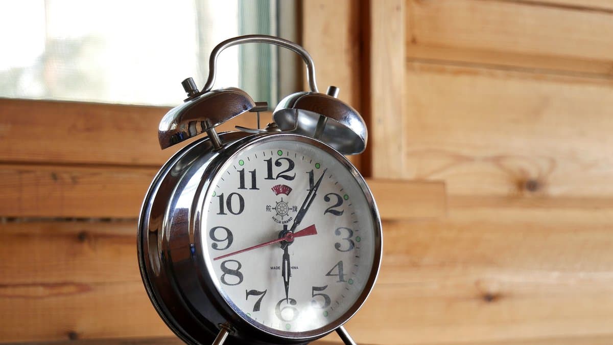 A classic red twin-bell mechanical alarm clock with a white face and black hands.