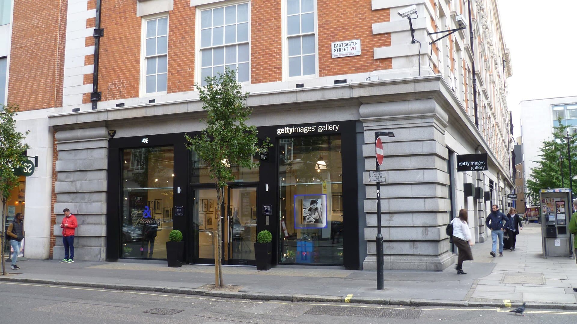 Corner shopfront of the Getty Images Gallery on Eastcastle Street, London, with black window frames, framed prints inside and pedestrians on the pavement.