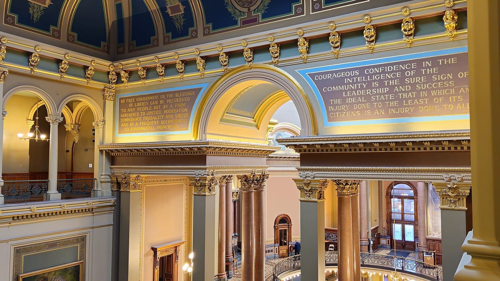 Ornate interior of the Iowa State Capitol, with gilded columns, painted arches and balconied galleries beneath a decorated ceiling.