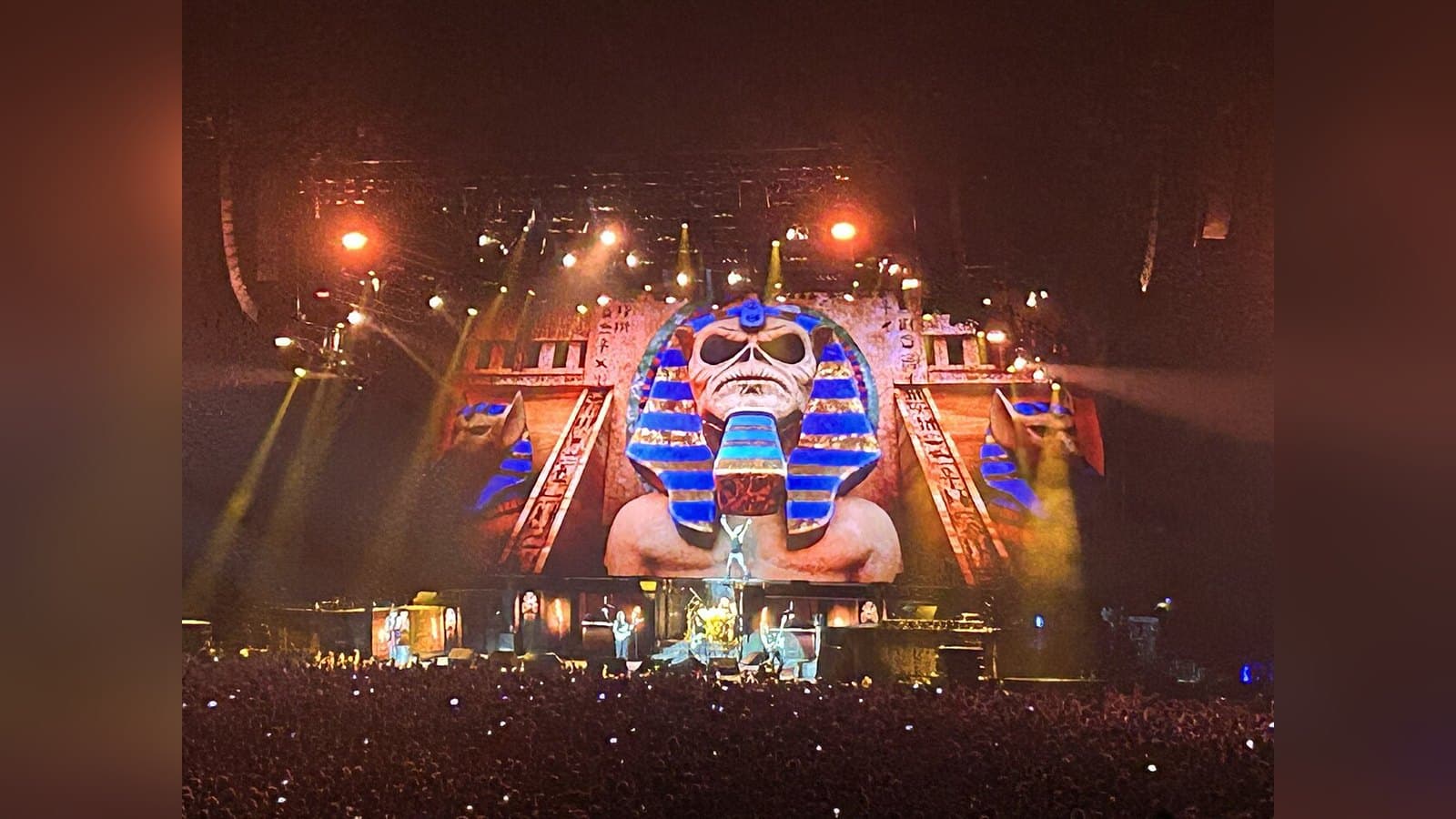 Iron Maiden's Egyptian-themed stage set glows orange and gold above a packed arena floor during the song Powerslave.