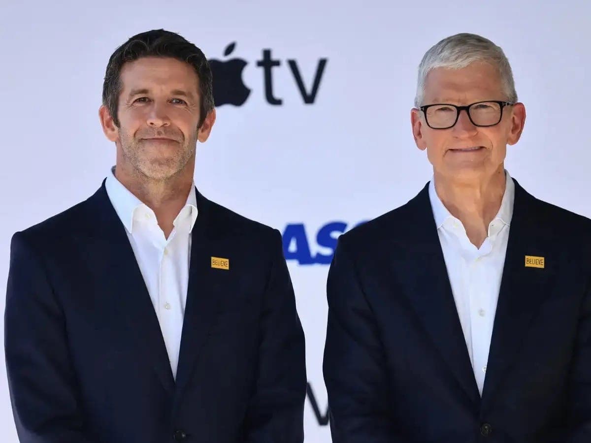 Tim Cook and John Ternus standing side by side in dark suits in front of an Apple TV backdrop.