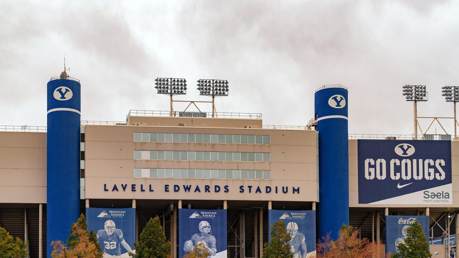 Exterior of LaVell Edwards Stadium at BYU with blue towers, stadium lights and a Go Cougs banner.