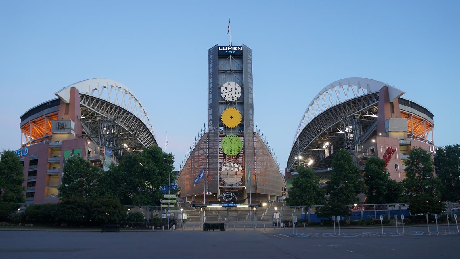 North side of Lumen Field in Seattle at dusk, with the stadium's twin roof arches and a lit clock tower between them.