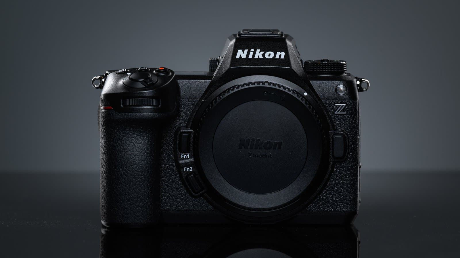 Front view of a black Nikon Z6 III full-frame mirrorless camera body with no lens attached, against a dark gray studio background.