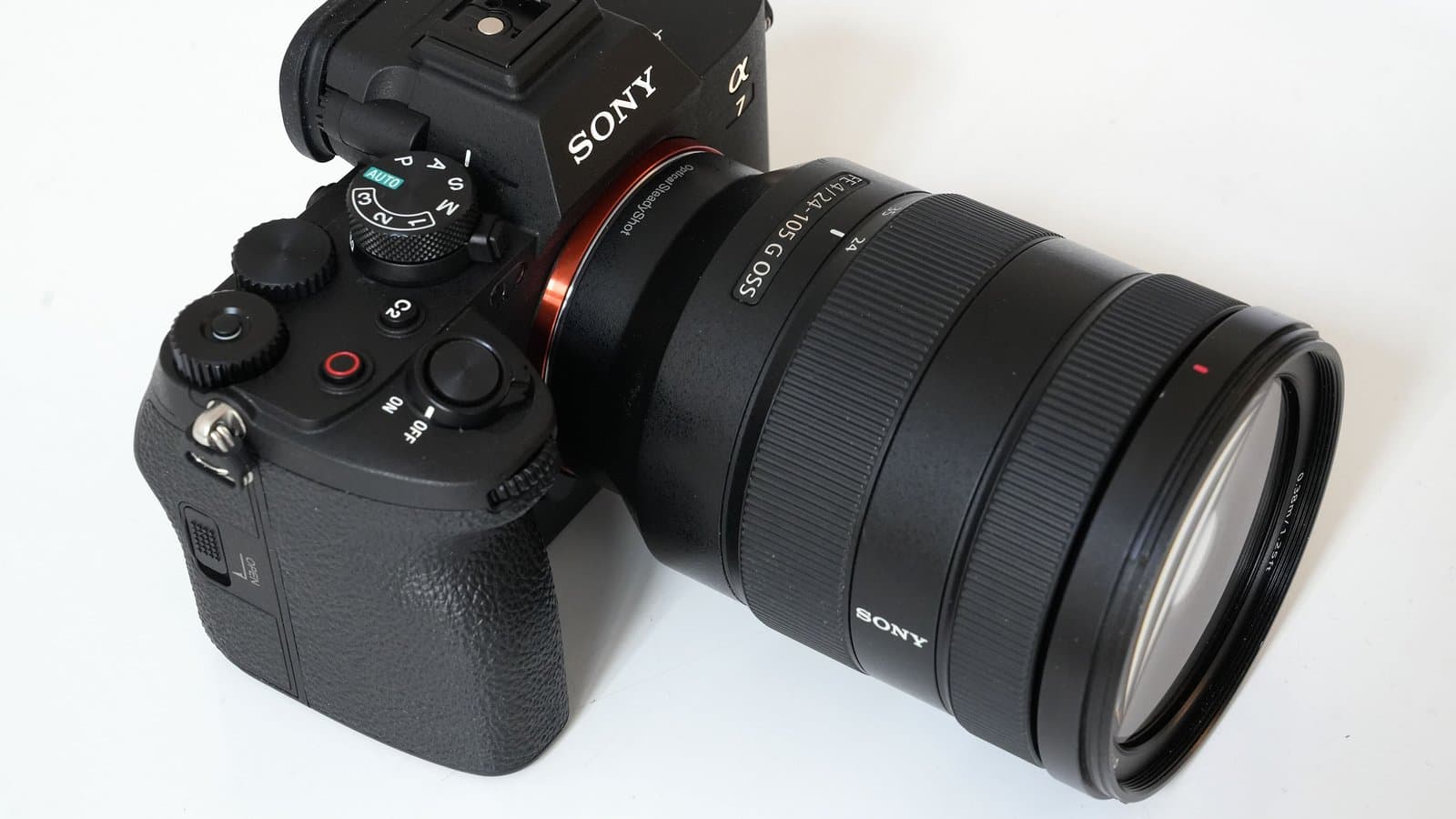 A black Sony Alpha 7 IV mirrorless camera body fitted with a large Sony zoom lens, photographed on a white background.