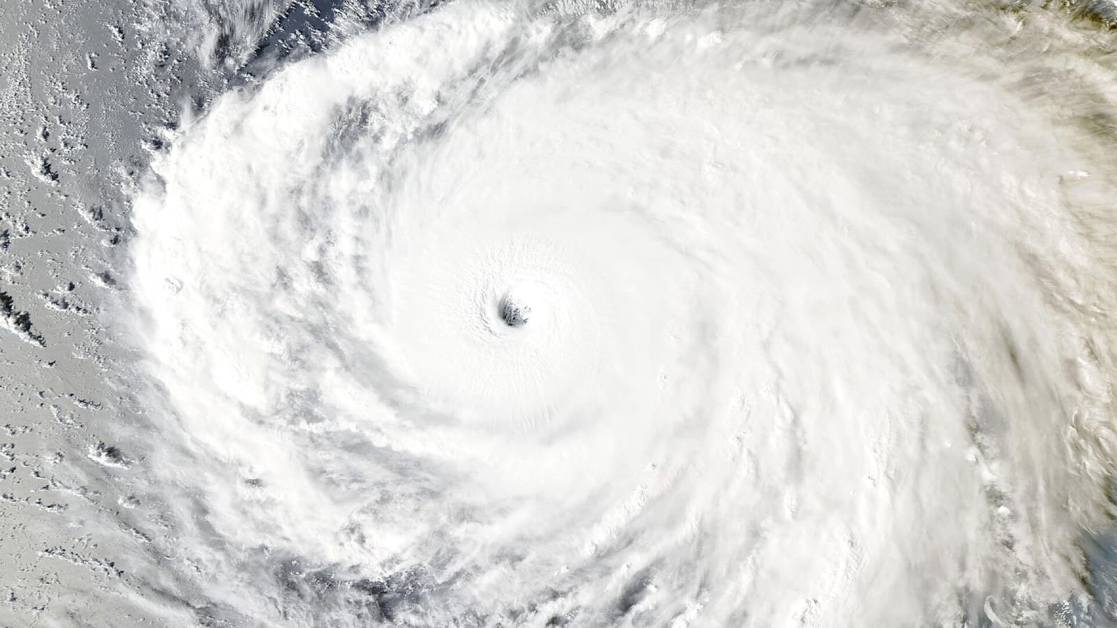 Satellite view of Super Typhoon Champi, a huge white spiral of clouds over the dark blue Pacific with a small, sharply defined eye at its center