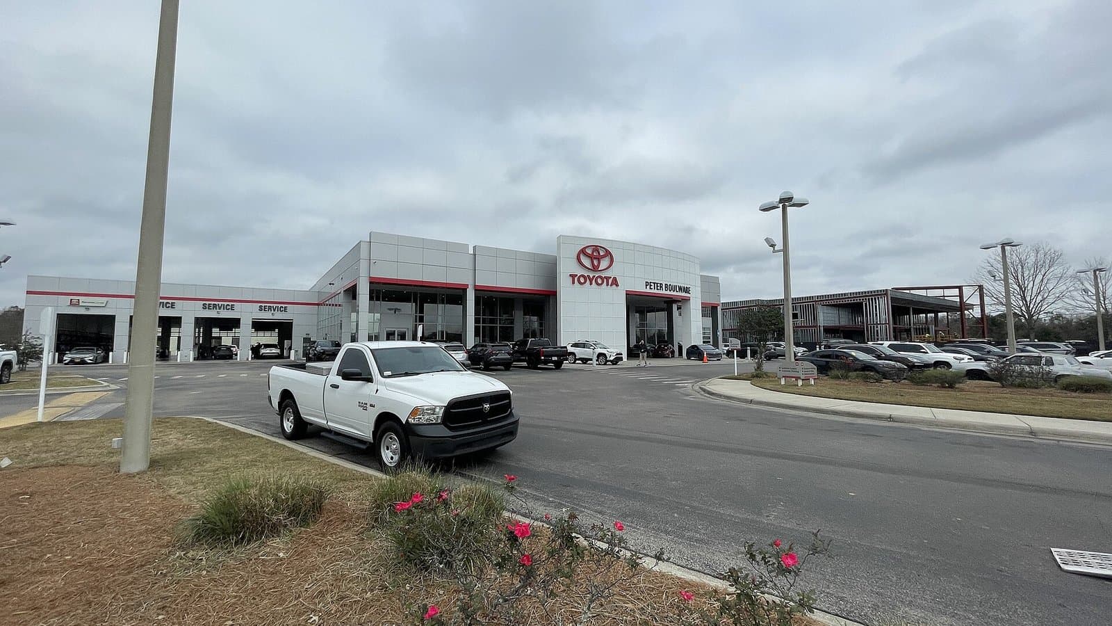 A Toyota car dealership building with a red logo and service lanes, with a white pickup truck parked in front.