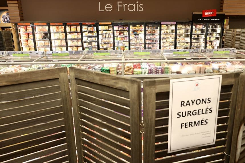 Supermarket frozen food aisles blocked off with wooden screens and a printed sign reading RAYONS SURGELES FERMES.