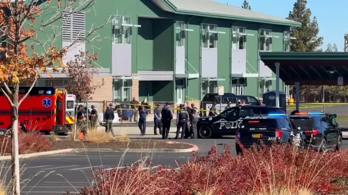 Police vehicles and people gathered outside the green-sided Silver Rail Elementary School building in southeast Bend.