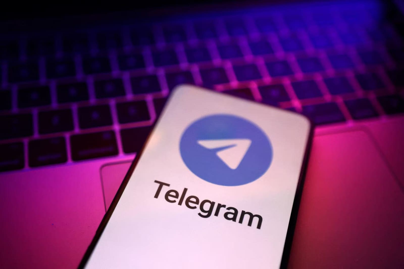 A smartphone displaying the Telegram logo, resting on a keyboard.
