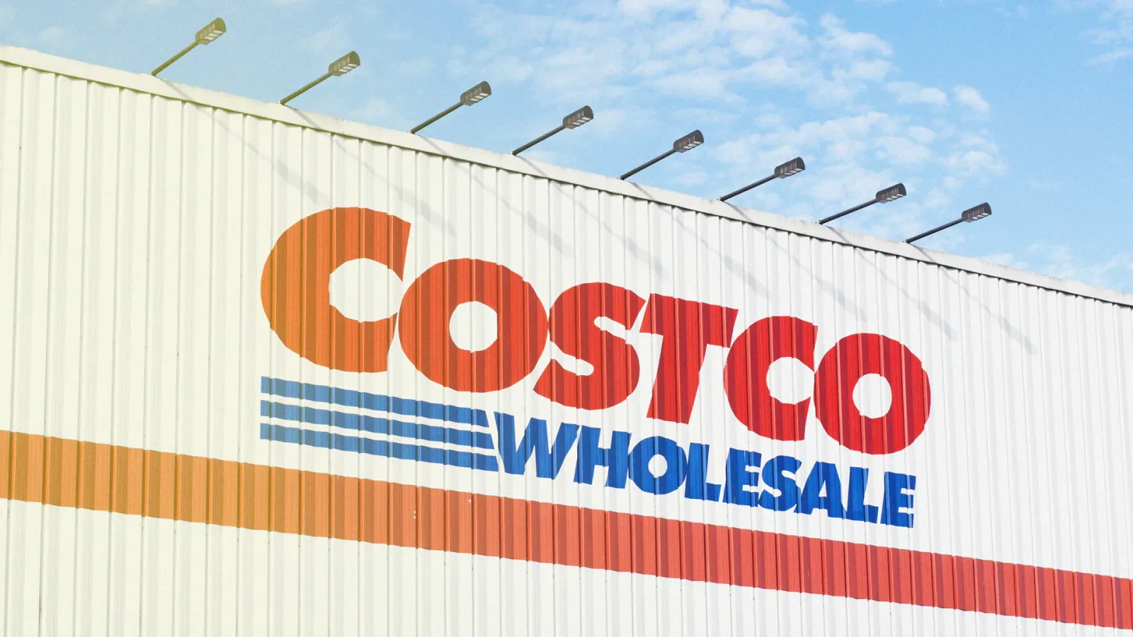 A Costco Wholesale storefront sign against a blue sky.
