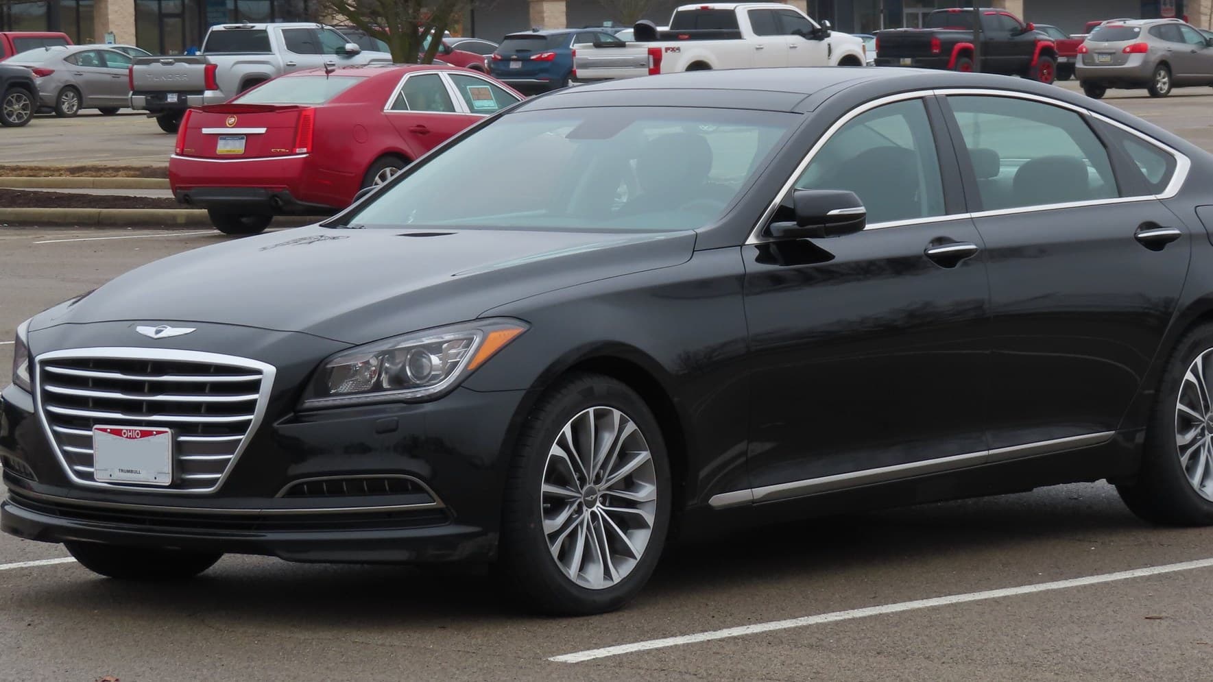 A black 2015 Hyundai Genesis luxury sedan parked in a shopping-center lot, seen from the front left.