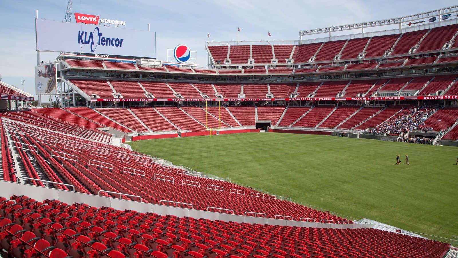 Empty red seats rising in tiers around the green field inside Levi's Stadium in Santa Clara, California.