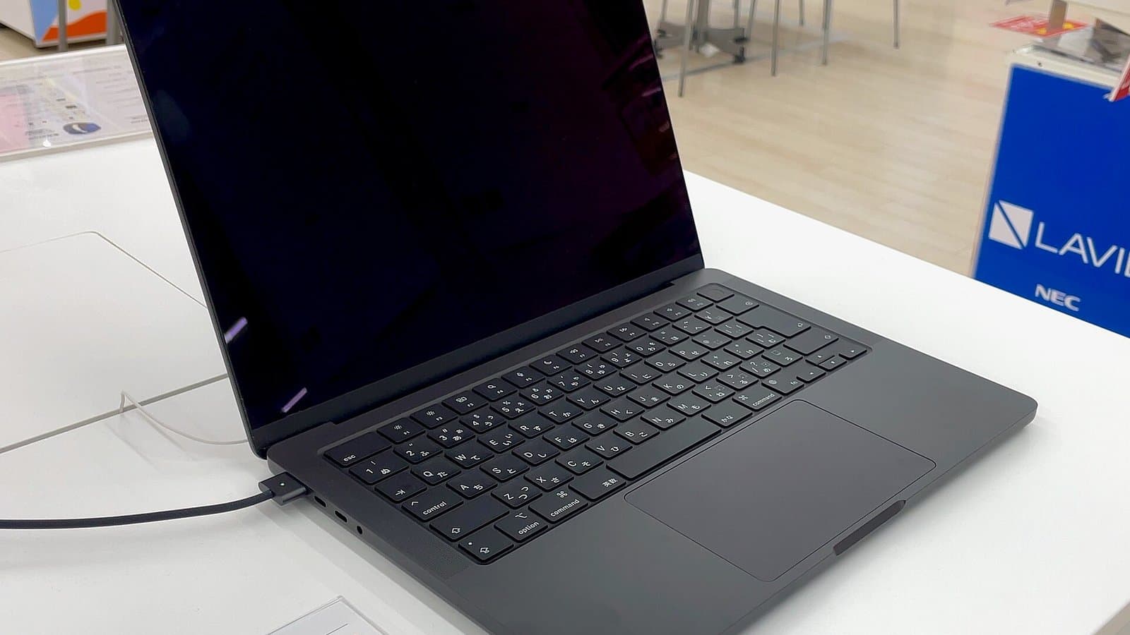 An open space gray 14-inch Apple MacBook Pro with M3 chip on a white display table in an electronics store.