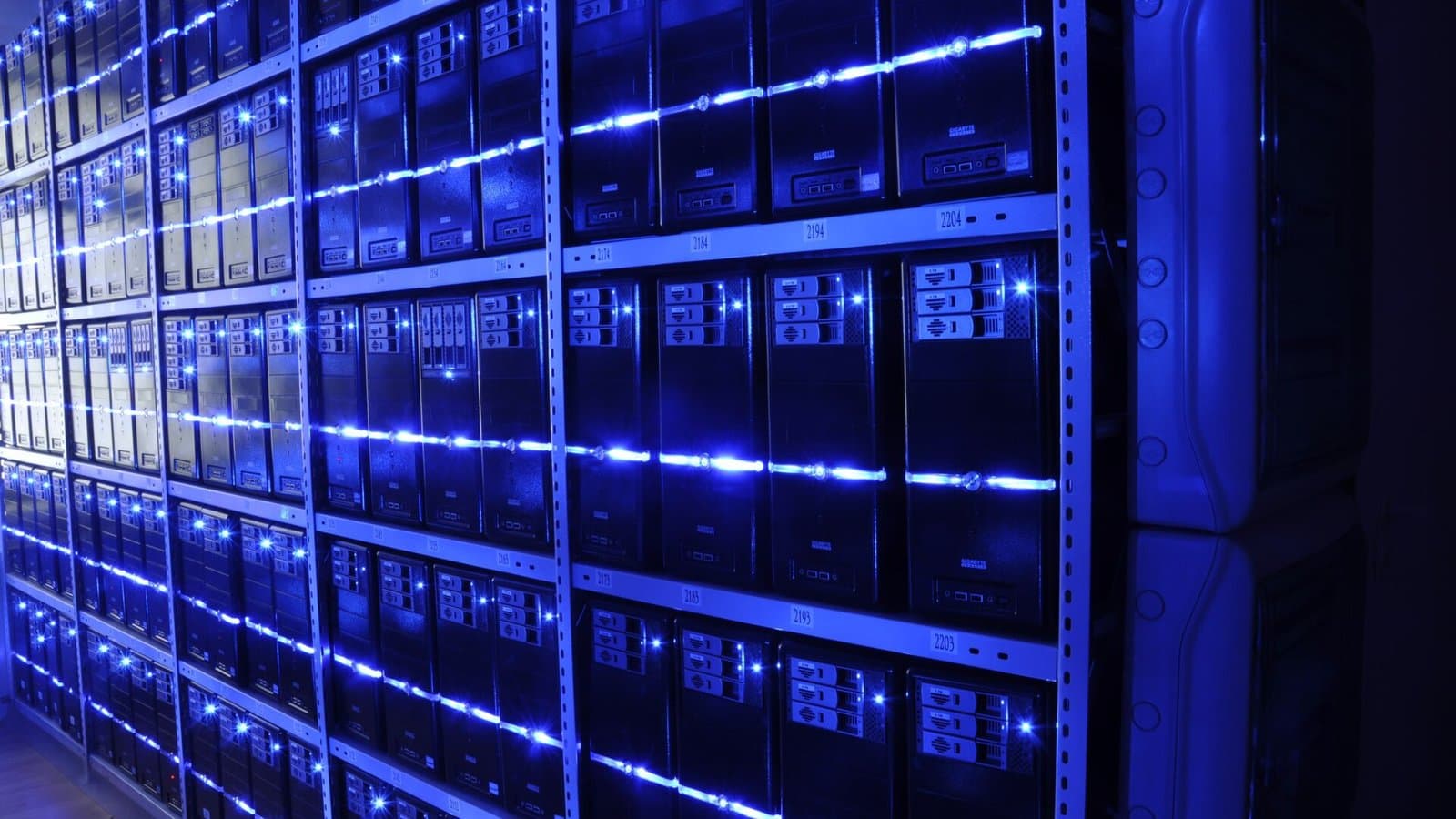 Rows of server racks lit in blue inside a data center server room.