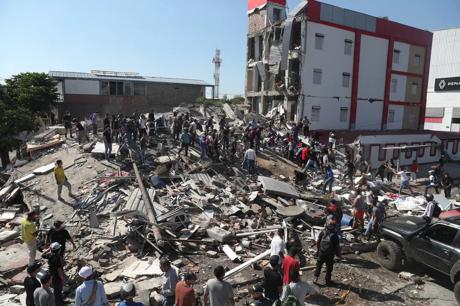 Residents and rescue workers standing among the rubble of a collapsed building in Cali.