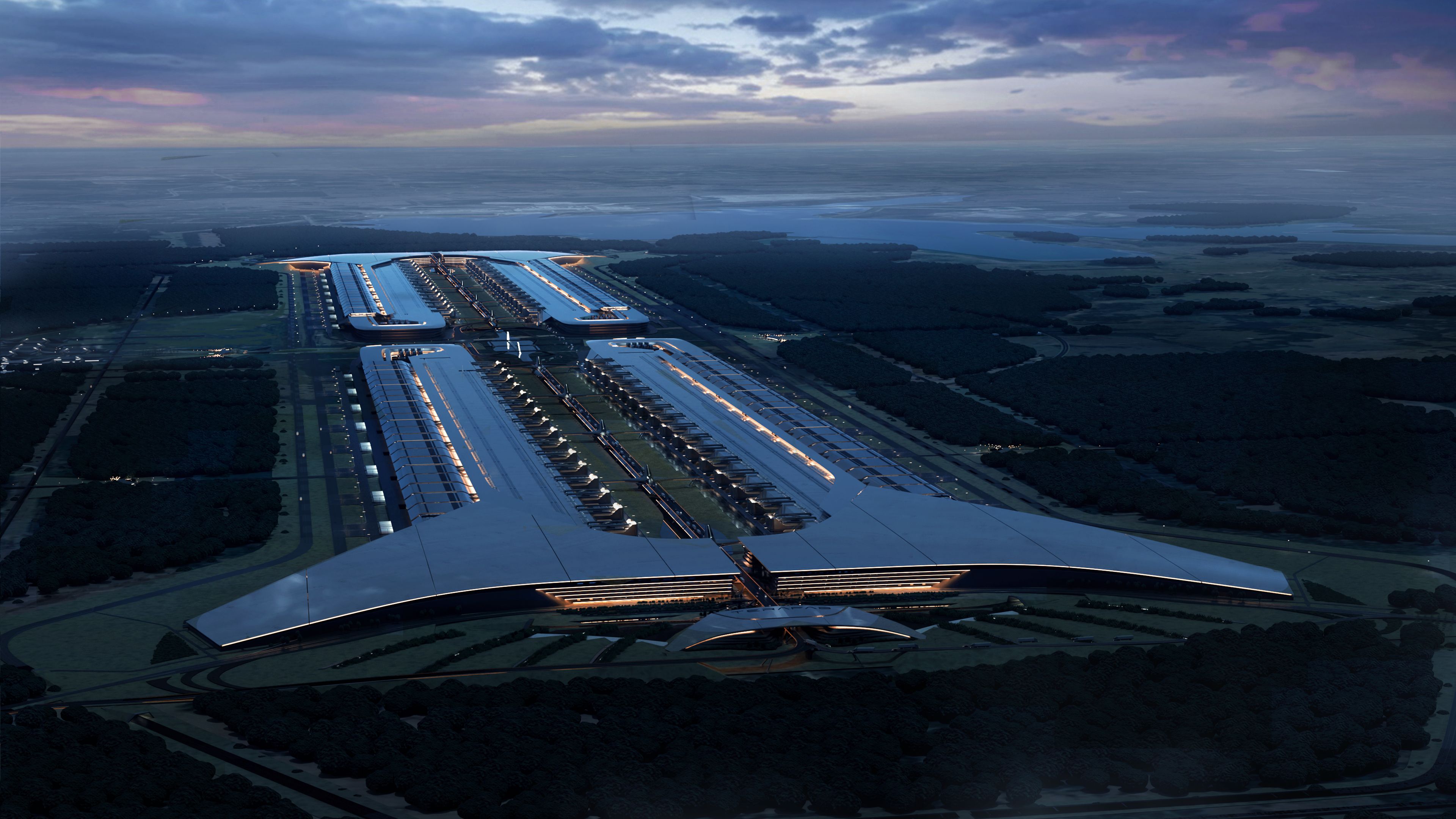 An aerial view at dusk of a vast industrial semiconductor facility beside water.