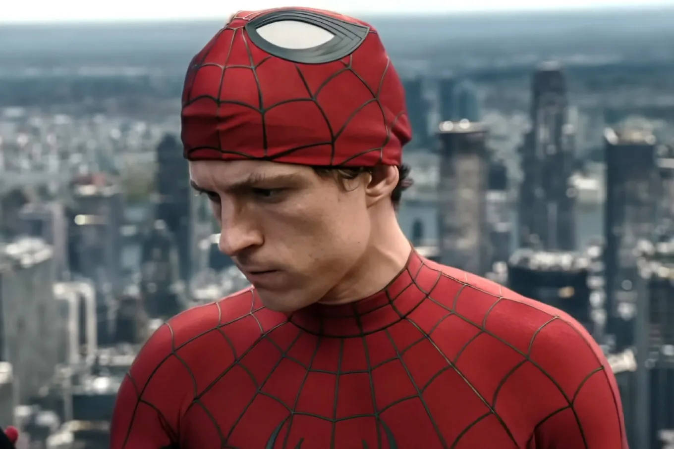Spider-Man in a makeshift red mask standing on a rooftop above a city skyline.