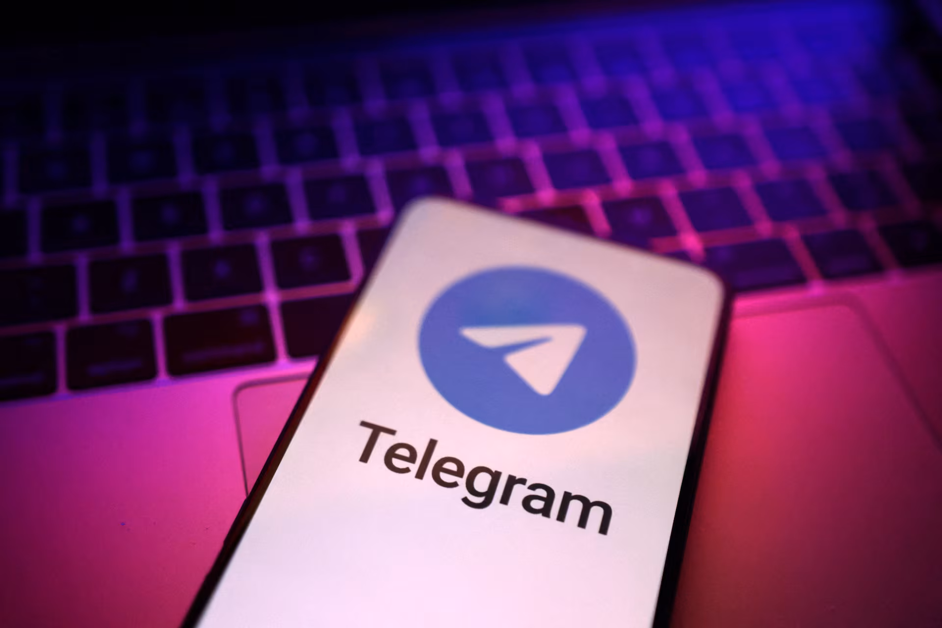 A smartphone displaying the Telegram logo, resting on a keyboard.