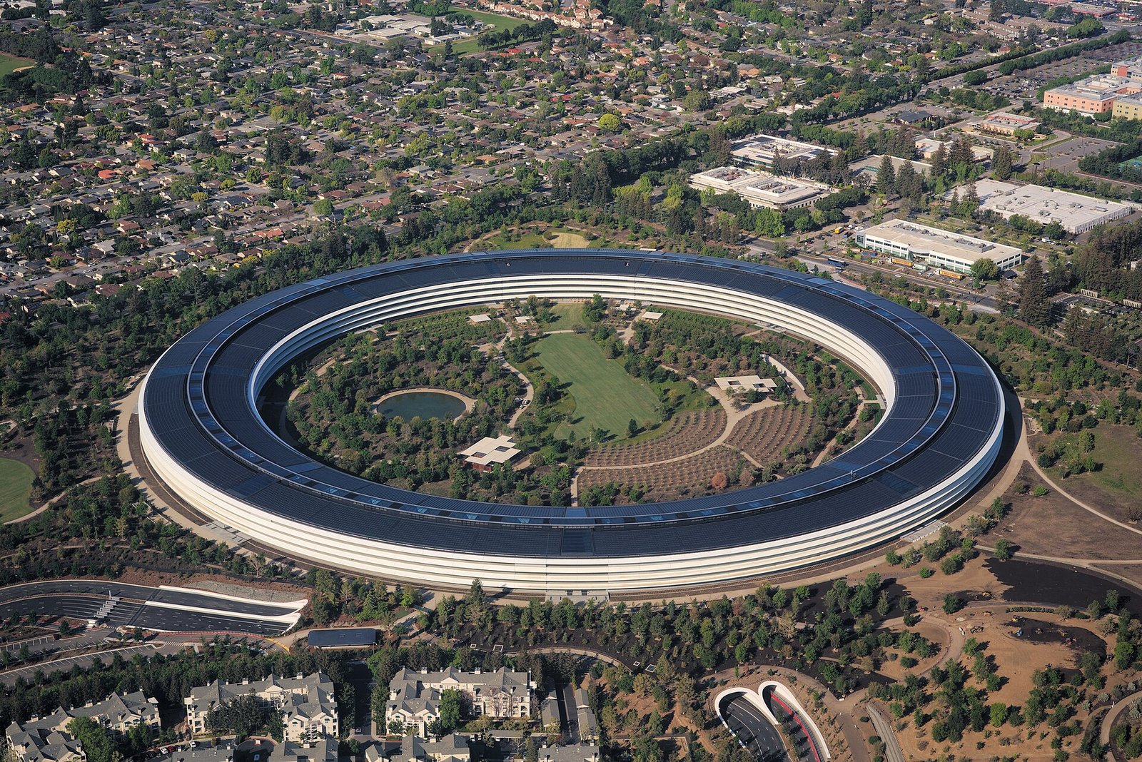 Aerial view of Apple Park in Cupertino, the ring-shaped Apple headquarters building surrounded by trees and a central garden.
