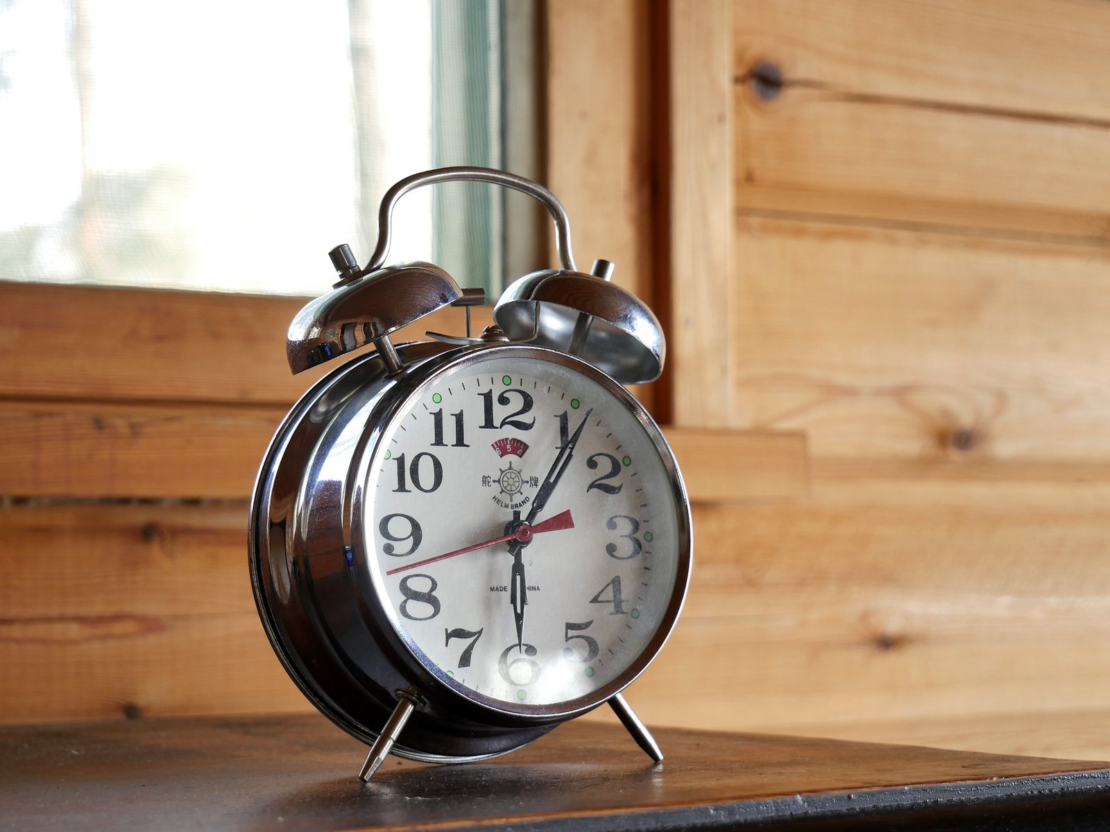 A classic red twin-bell mechanical alarm clock with a white face and black hands.