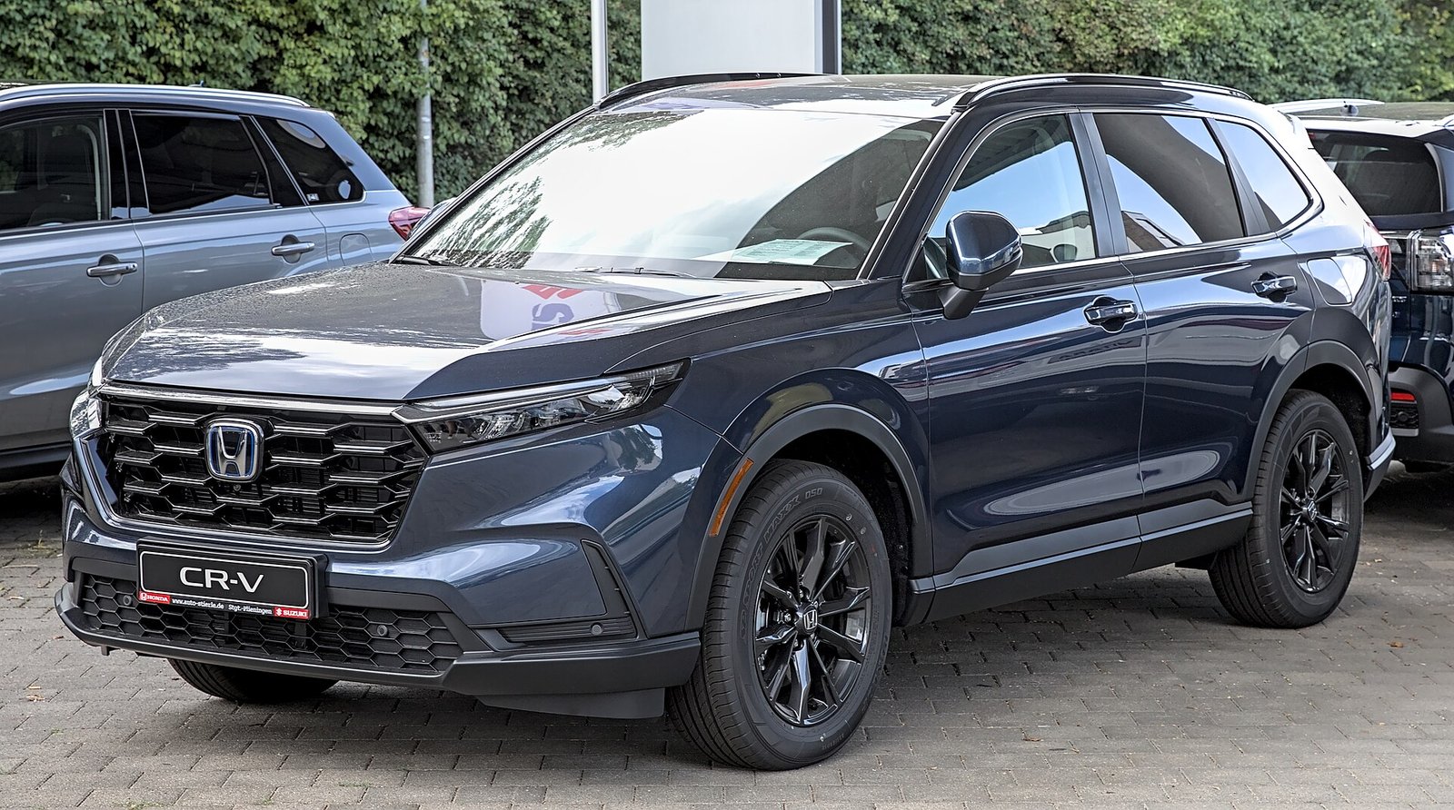 A dark blue sixth-generation Honda CR-V Hybrid SUV parked in a lot, seen from the front left.