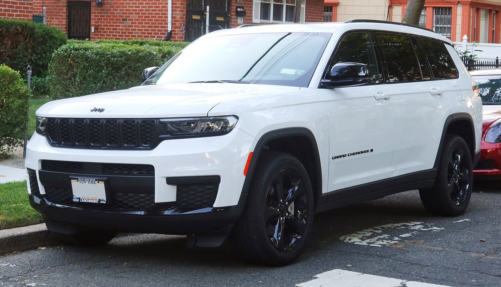 A white 2021 Jeep Grand Cherokee L three-row SUV parked at a curb, seen from the front.