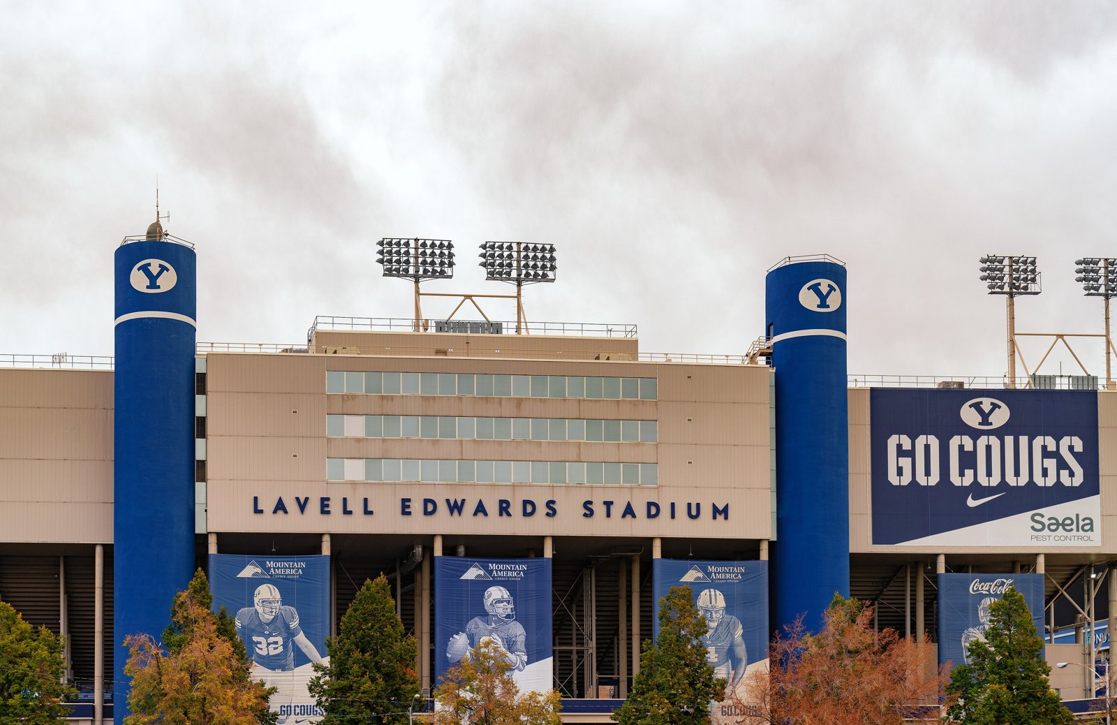 Exterior of LaVell Edwards Stadium at BYU with blue towers, stadium lights and a Go Cougs banner.