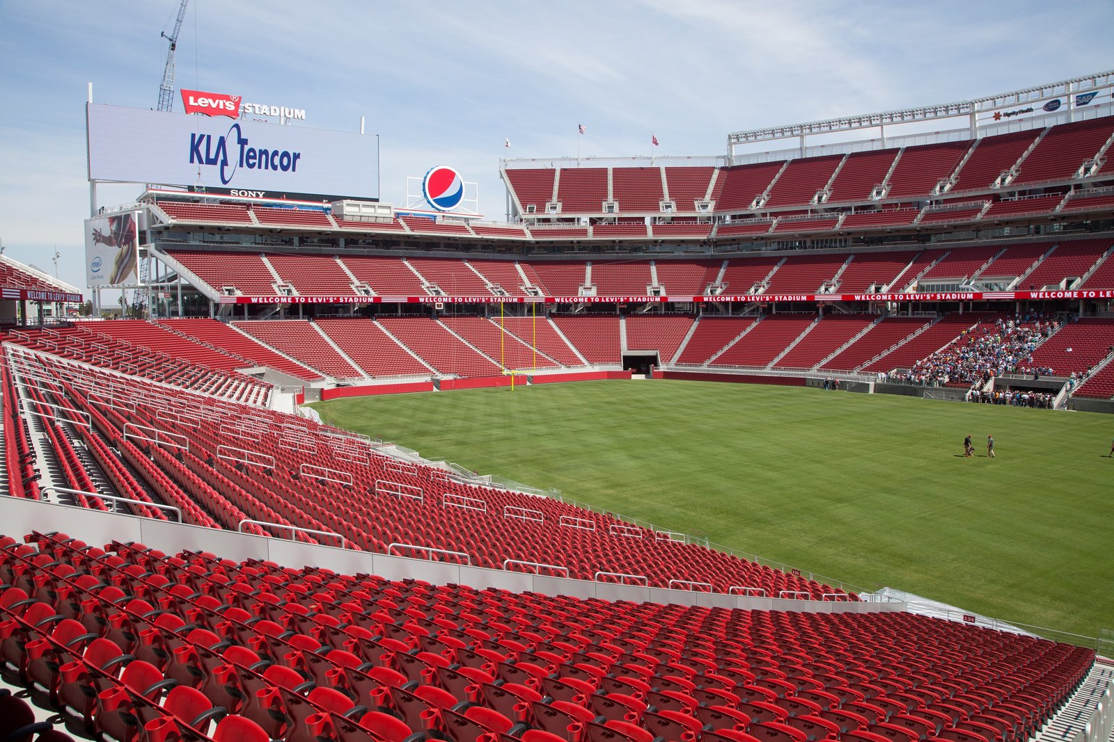 Empty red seats rising in tiers around the green field inside Levi's Stadium in Santa Clara, California.