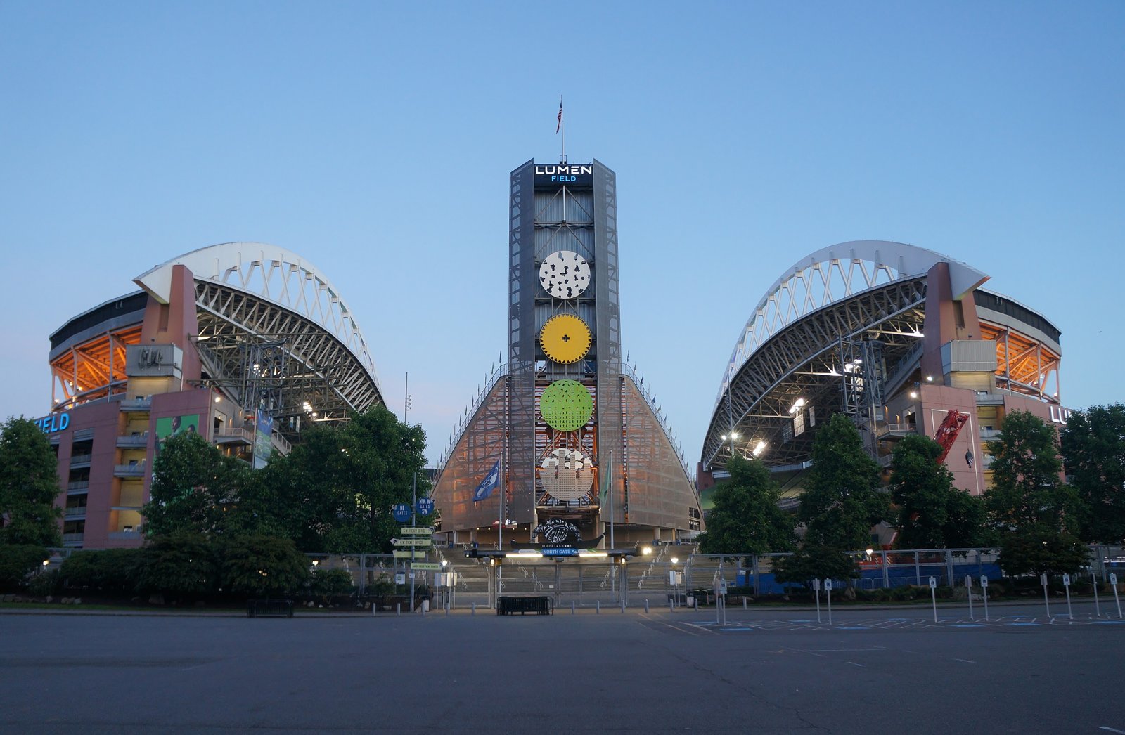 North side of Lumen Field in Seattle at dusk, with the stadium's twin roof arches and a lit clock tower between them.