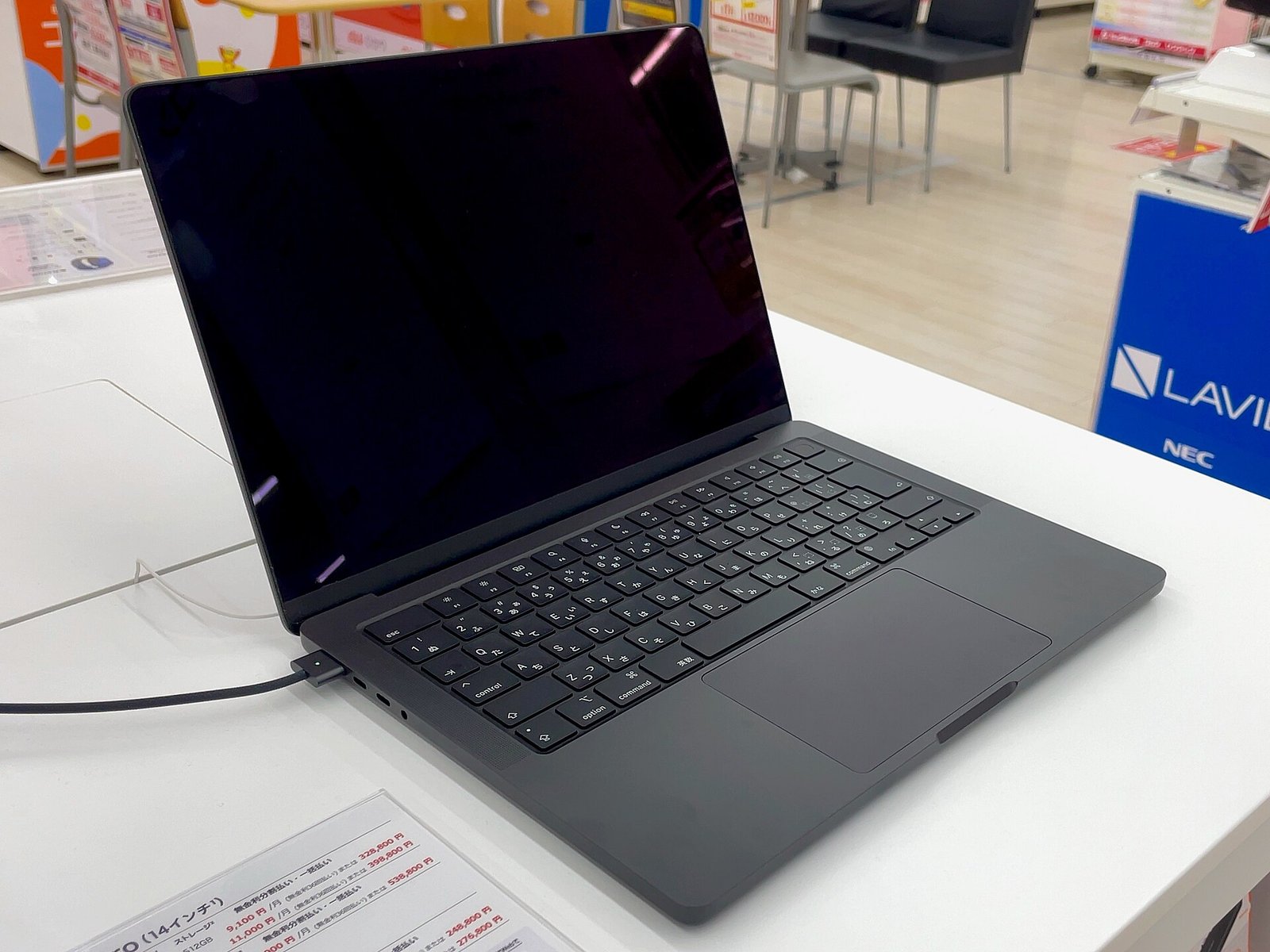 An open space gray 14-inch Apple MacBook Pro with M3 chip on a white display table in an electronics store.