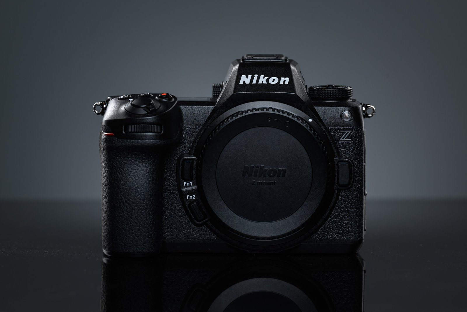 Front view of a black Nikon Z6 III full-frame mirrorless camera body with no lens attached, against a dark gray studio background.