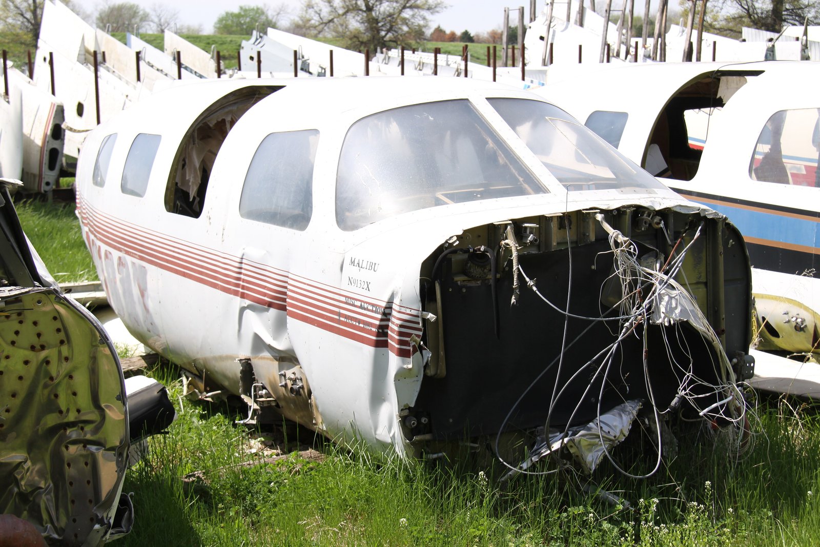 A white single-engine Piper PA-46 Malibu airplane with red and blue stripes parked on an airport ramp.
